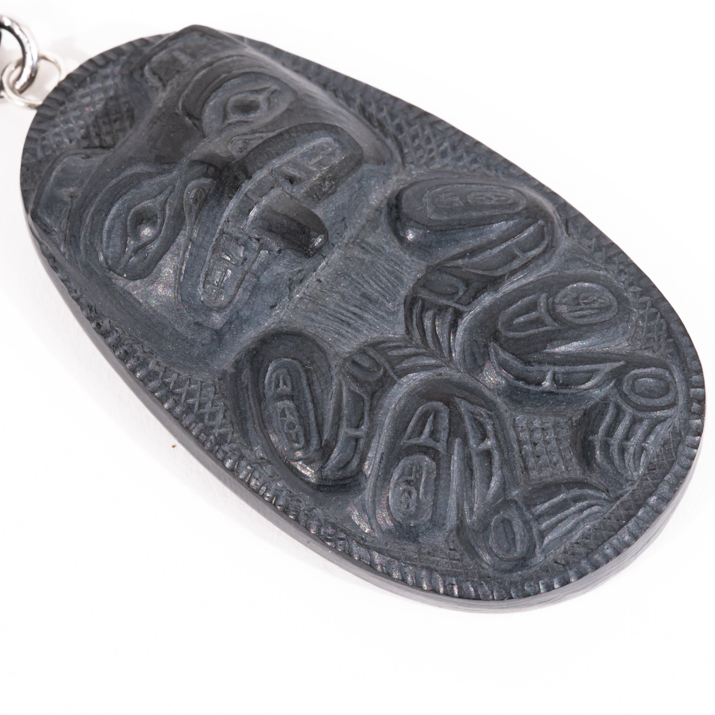 Close up of  Black Argillite Bear pendant necklace with intricate Haida Carvings showcasing the 3-d depth of the carving on a white background made by Local Haida Gwaii Artist Melanie Russ