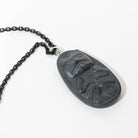 Close up of left side of Black Argillite Bear pendant necklace with intricate Haida Carvings showcasing the 3-d depth of the carving on a white background made by Local Haida Gwaii Artist Melanie Russ