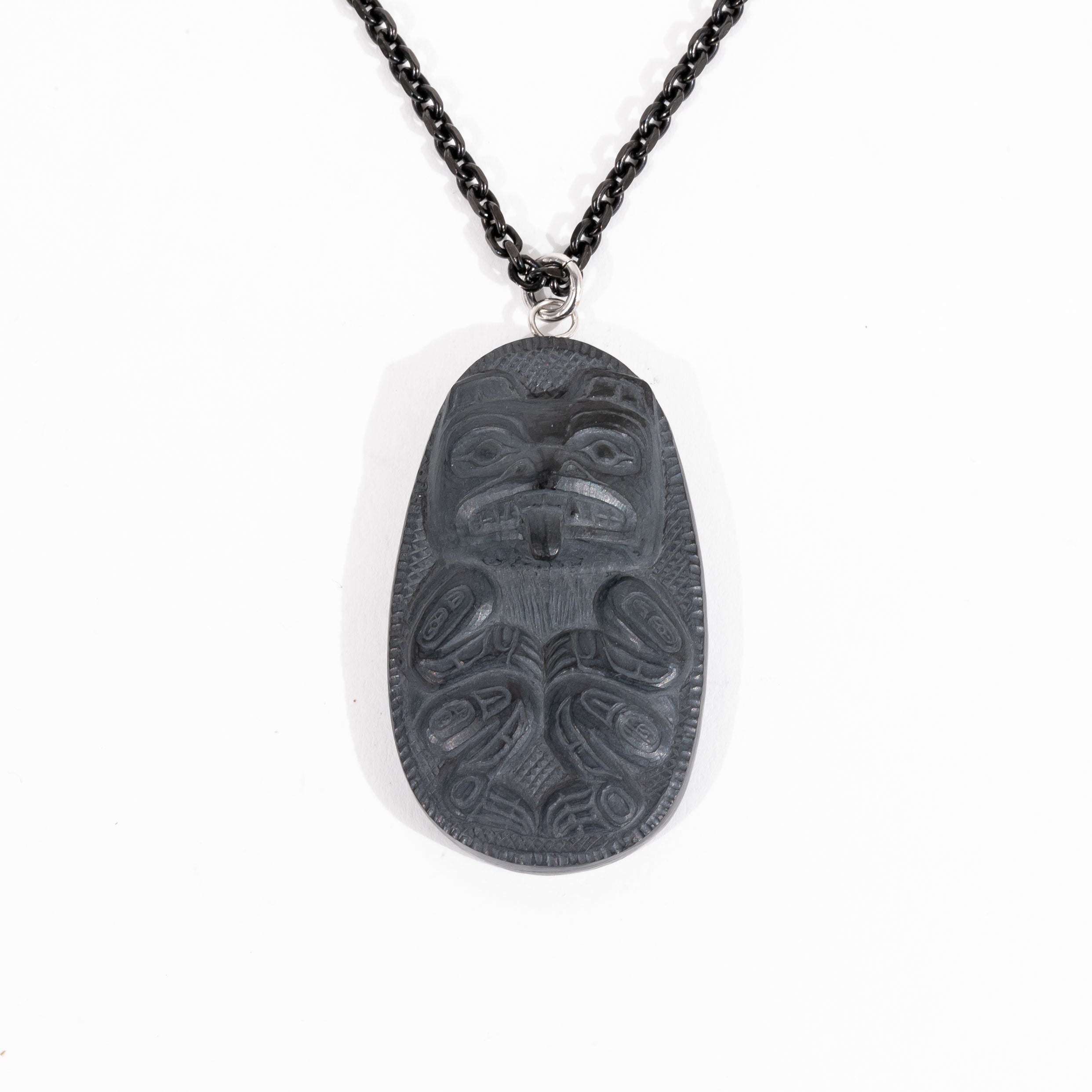 Front of Black Argillite Bear pendant necklace with intricate Haida Carvings showcasing the 3-d depth of the carving on a white background made by Local Haida Gwaii Artist Melanie Russ