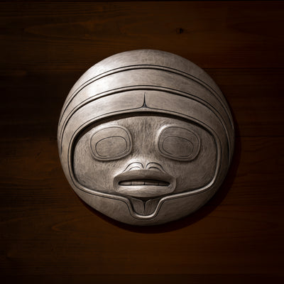 Fungus man mask casting with intricate carvings by Haida artist Cori Savard on a dark wooden background