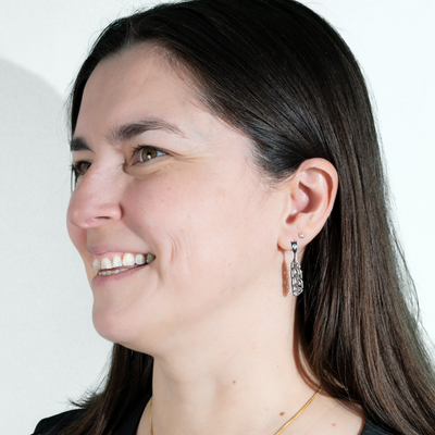 Life style photo of model wearing sterling silver gina mae manifesto feather earrings smiling and looking of into the distance