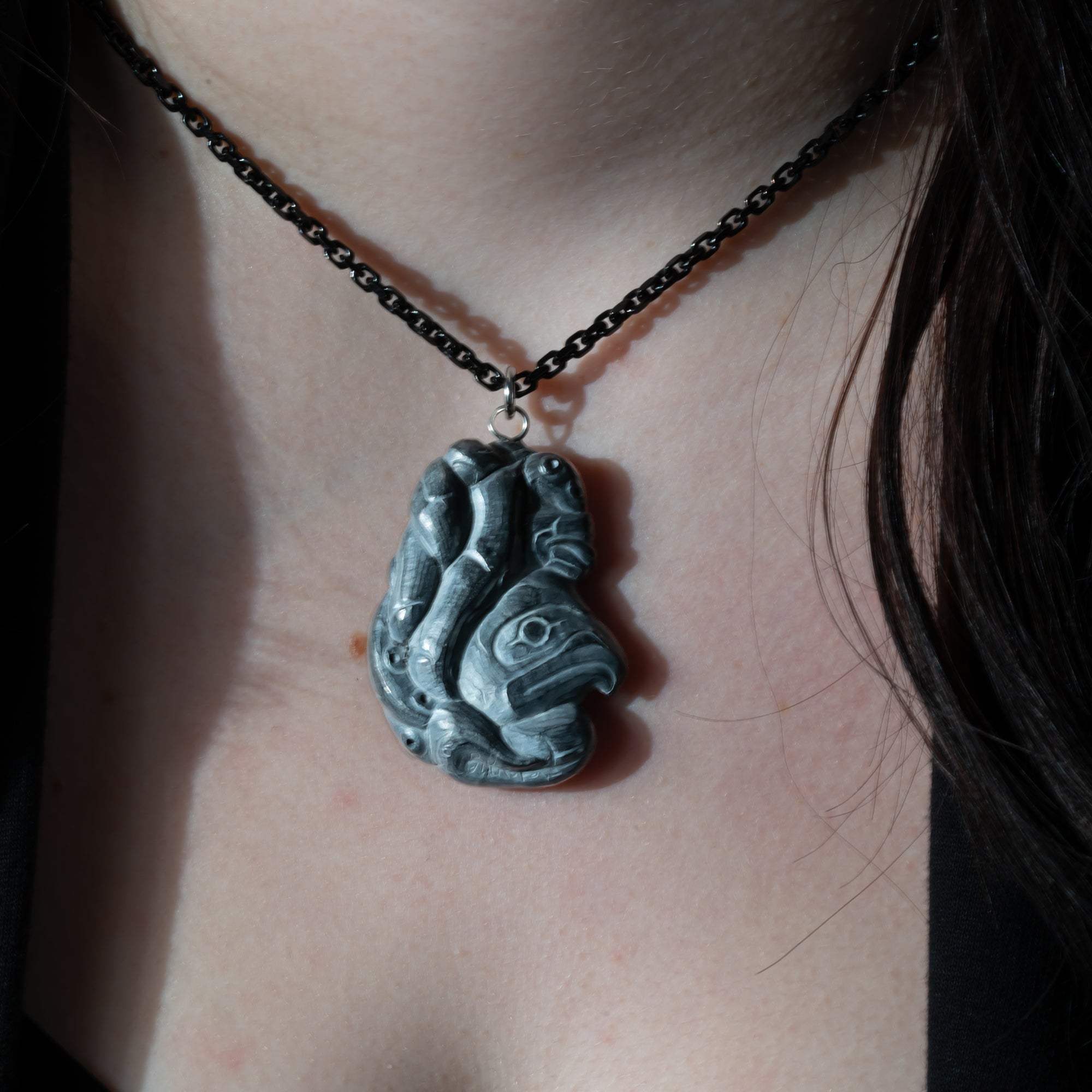 model wearing Black Argillite Octopus pendant necklace with intricate Haida Carvings on a white background made by Local Haida Gwaii Artist Melanie Russ