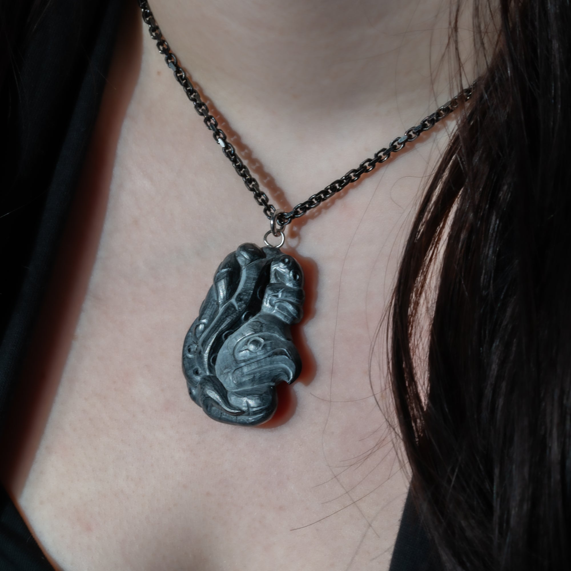 Close up of side of Black Argillite Octopus pendant necklace with intricate Haida Carvings on a white background made by Local Haida Gwaii Artist Melanie Russ