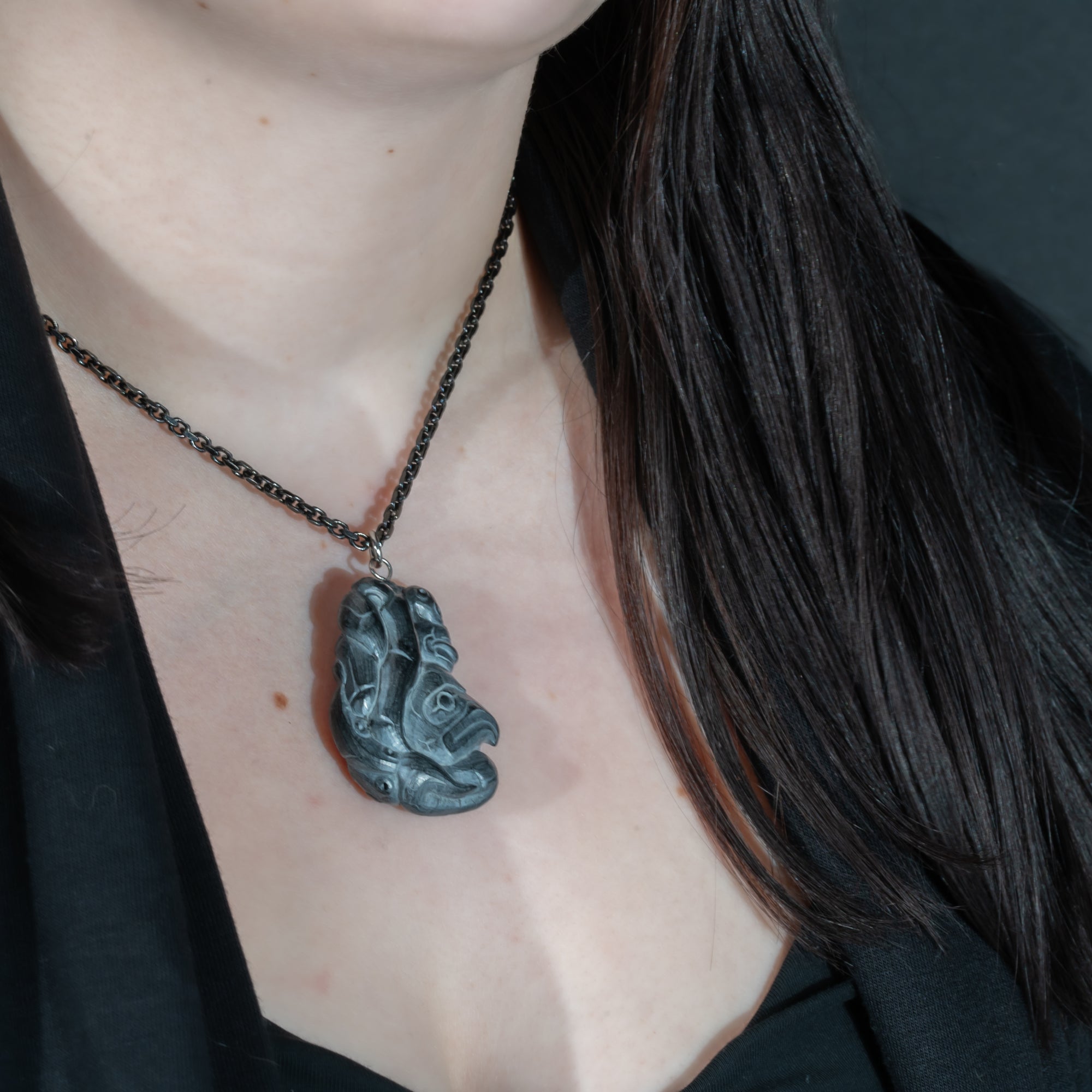 Close up of left of Black Argillite Octopus pendant necklace with intricate Haida Carvings on a white background made by Local Haida Gwaii Artist Melanie Russ