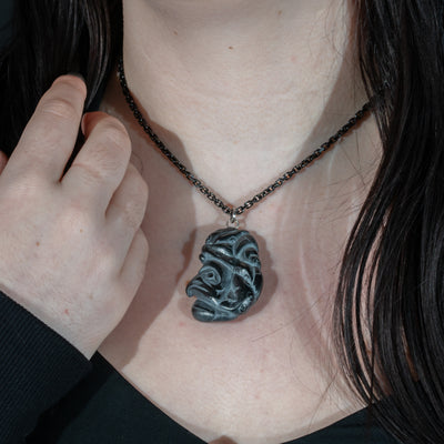 Close up of tentacles wrapping around both sides of Black Argillite Octopus pendant necklace with intricate Haida Carvings on a white background made by Local Haida Gwaii Artist Melanie Russ
