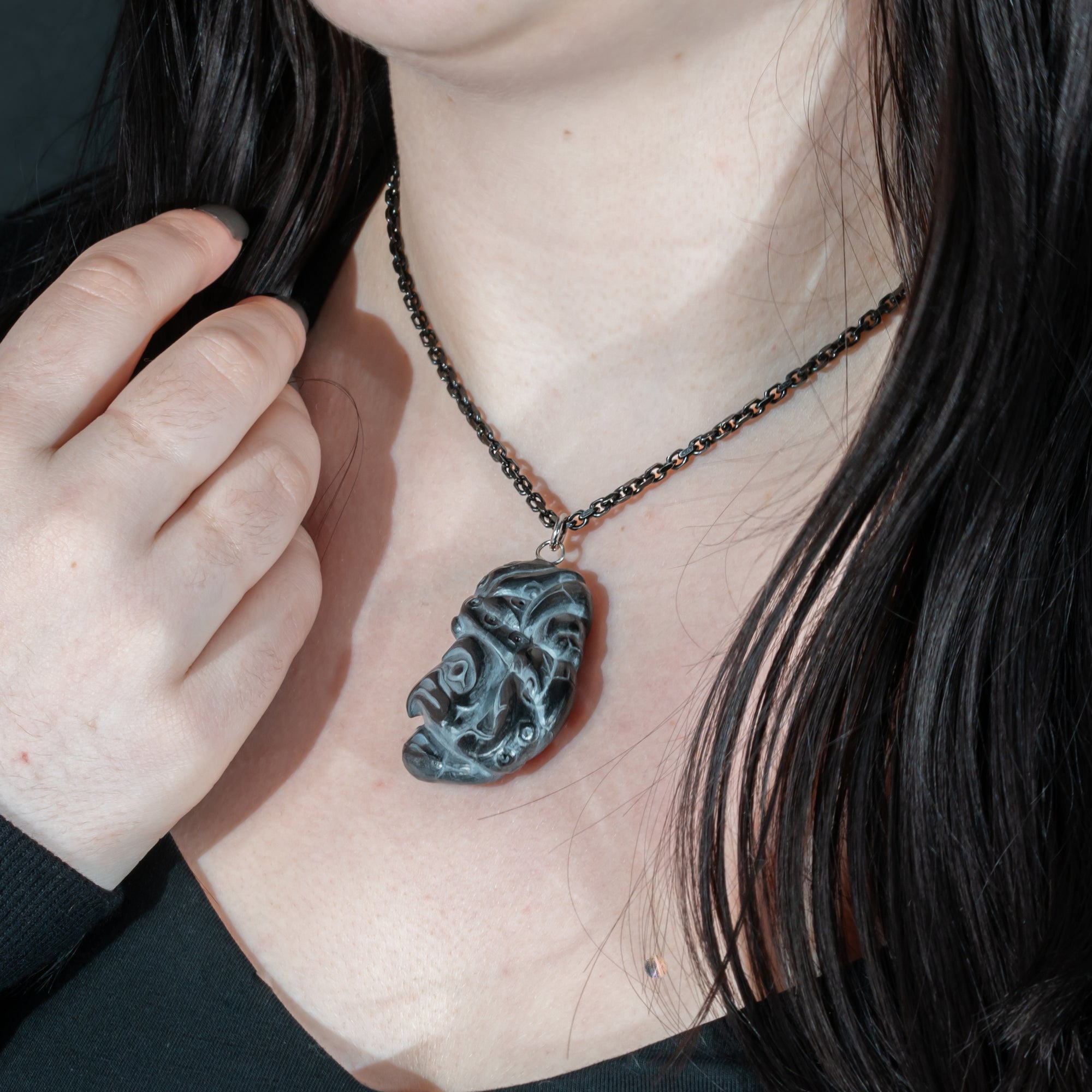Close up of tentacles wrapping around both sides of Black Argillite Octopus pendant necklace with intricate Haida Carvings on a white background made by Local Haida Gwaii Artist Melanie Russ
