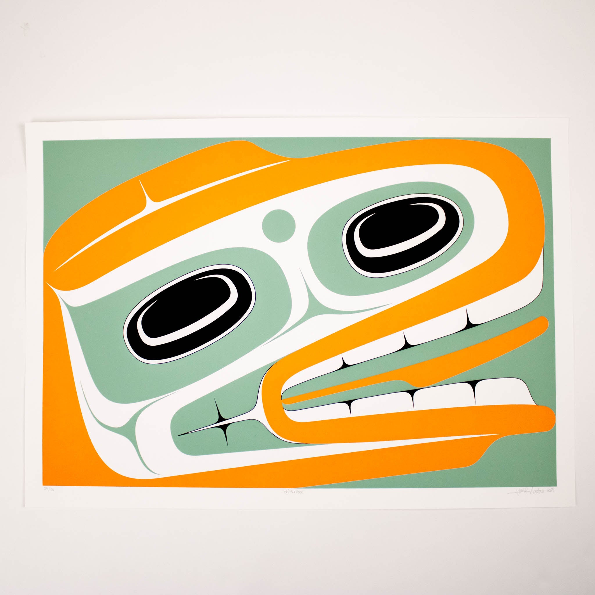 Framed artwork of a stylized face with orange, green, and black colors on a light gray background.