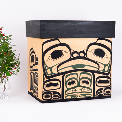 Cedar Bentwood Chest featuring bear mother and her cubs as well as mouse women in a forest colour palette on a white bak ground with haida gwaii huckle berries beside it