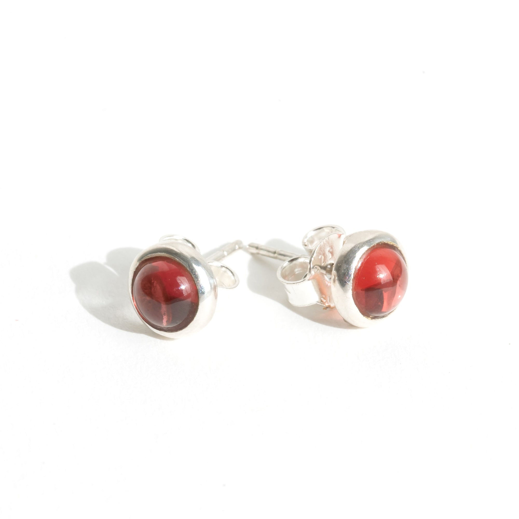 Round red garnet and sterling silver stud earrings on a white background