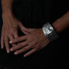 Close-up of hands with a Sterling Silver cuff bracelet with intricate Eagle and Salmon Repoussé design on a black background