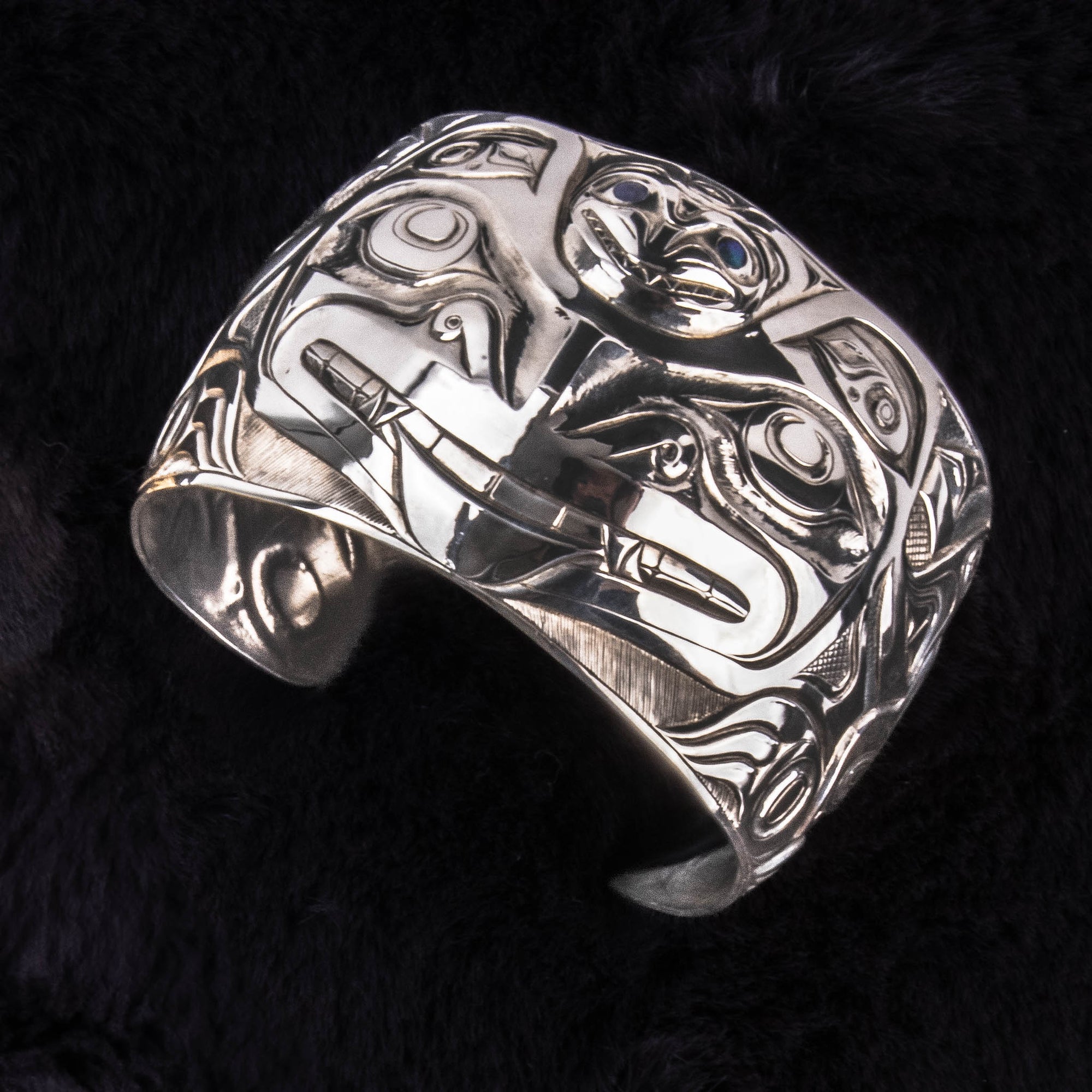 Sterling Silver Wasco and Killer Whale Repousse Bracelet by Jesse Brillon (Haida) on black background