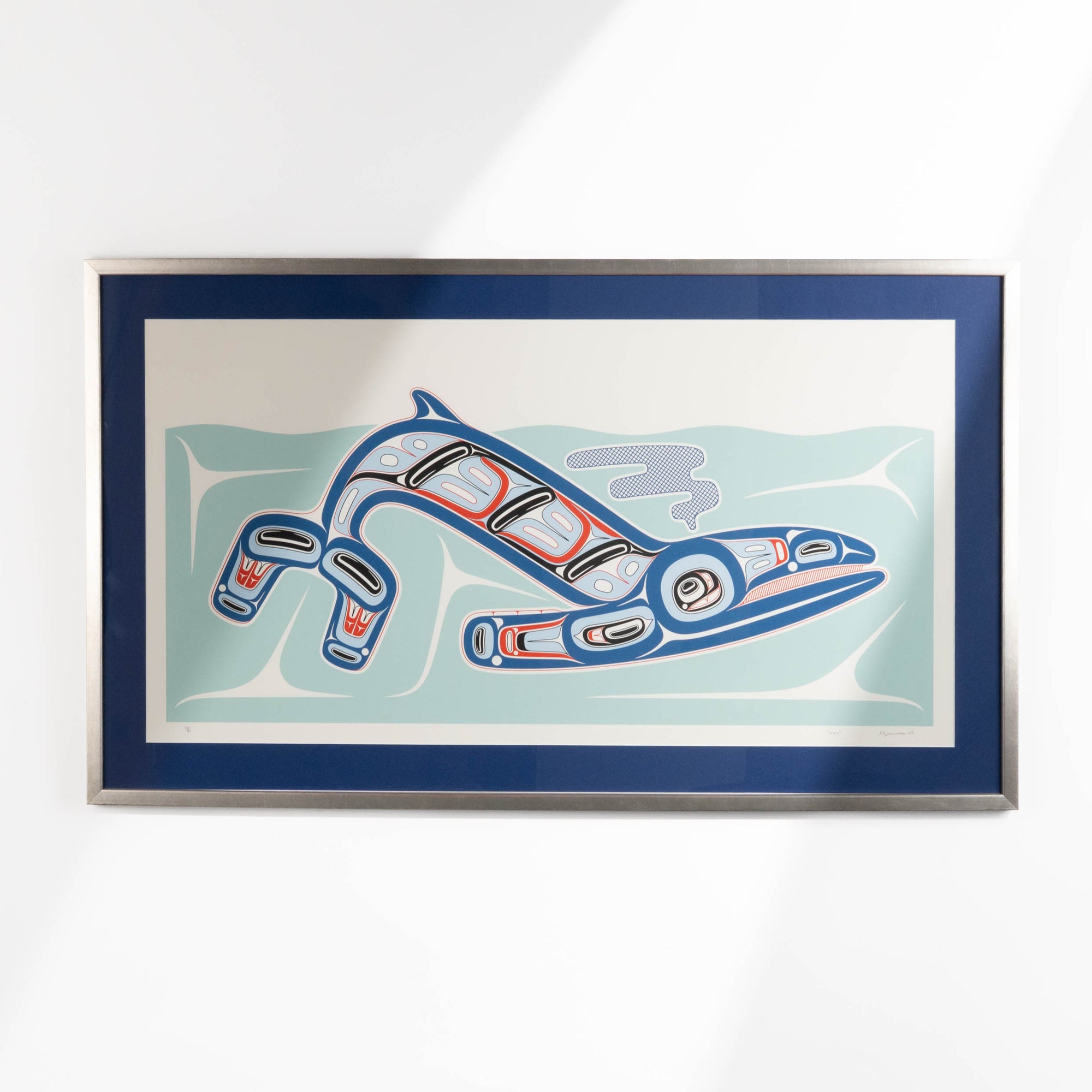 Framed artwork of a stylized haida formline whale swimming in the ocean with abstract patterns on a white background