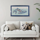 White sofa with decorative pillows in a room with a framed artwork of Kun (whale) Fine art print, showcasing a whale swimming through the ocean in Haida Formline on the wall.