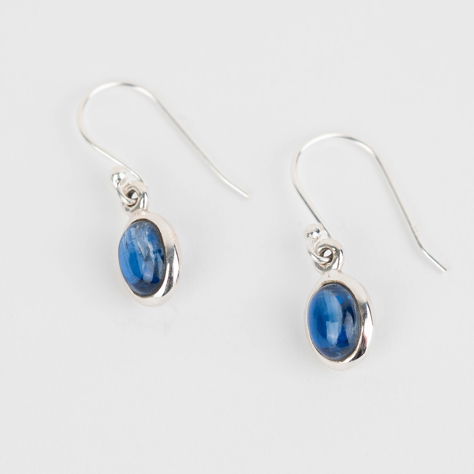 Pair of silver earrings with blue Kyanite stones on a white background