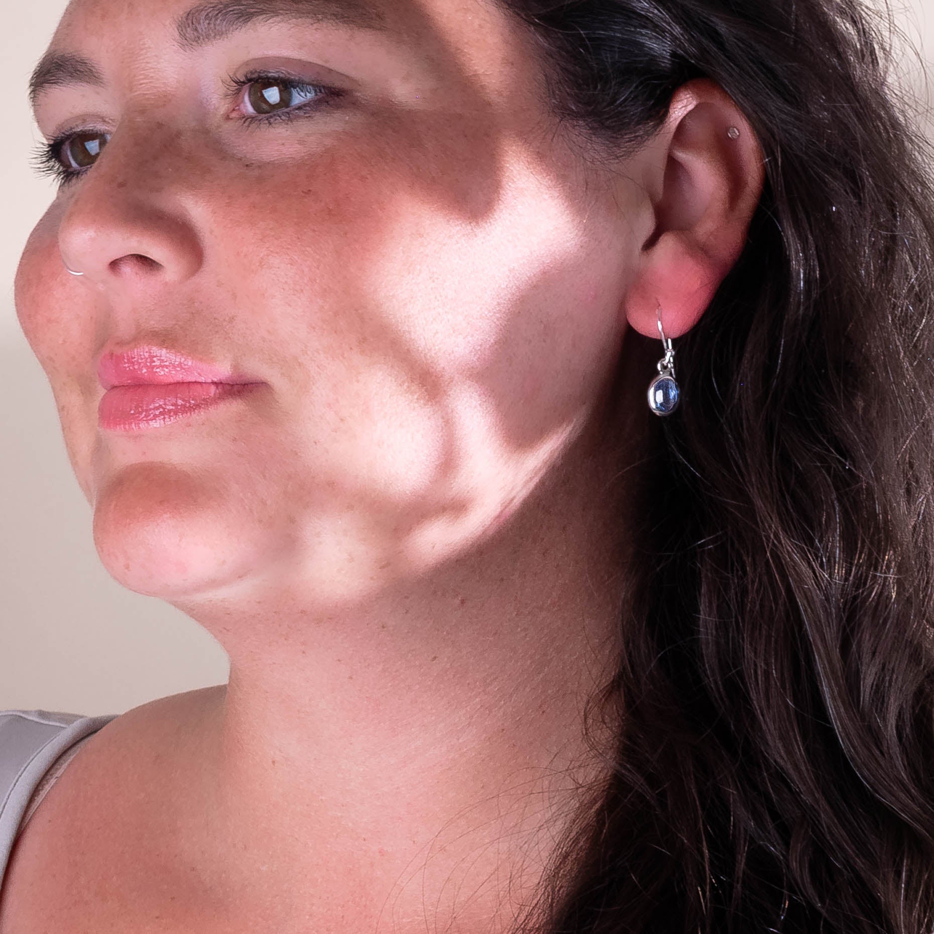Close-up of a woman wearing a silver earring with a Kyanite Stones.