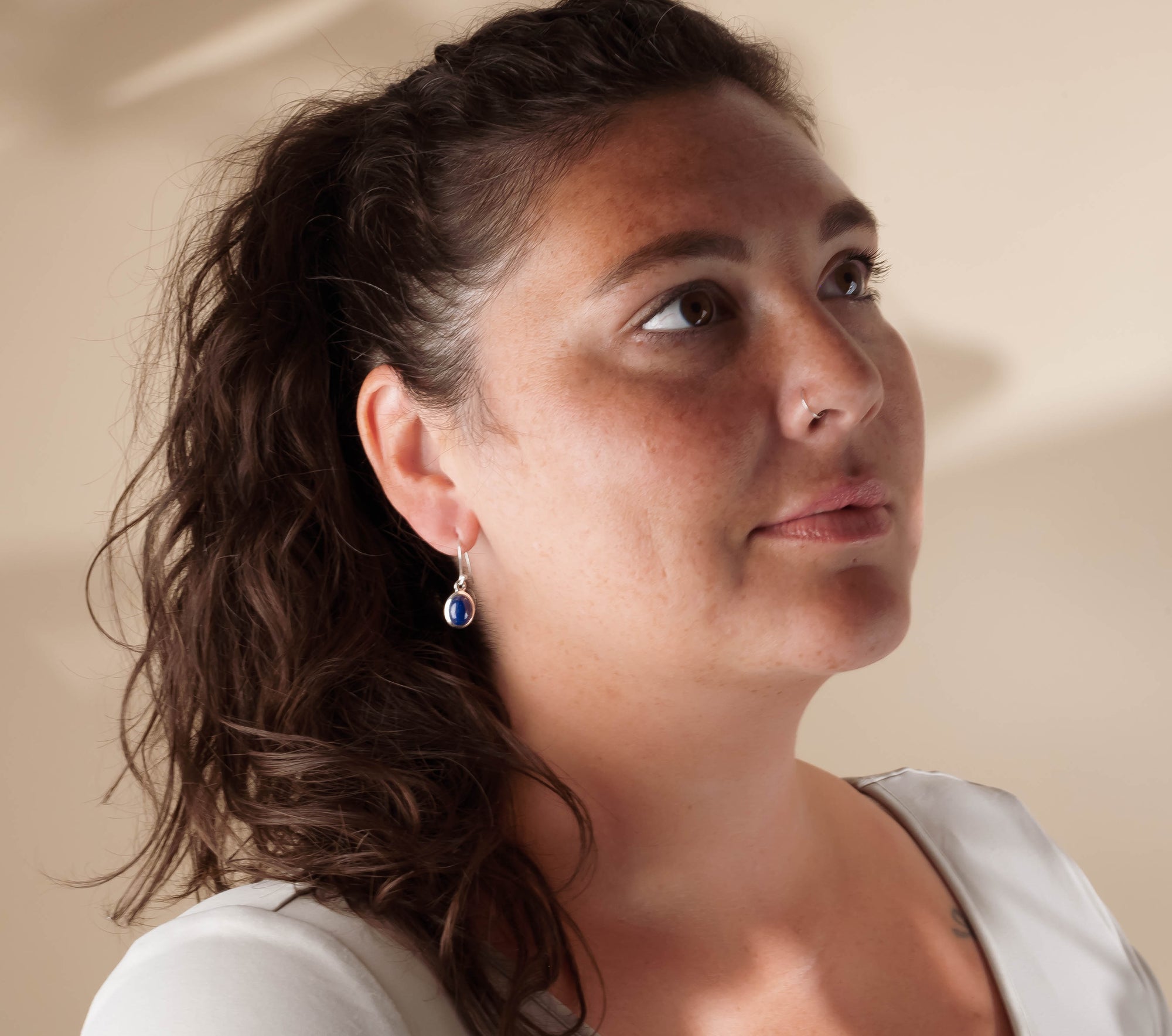 Woman with braided hair wearing Lapis Lazuli earrings against a neutral background