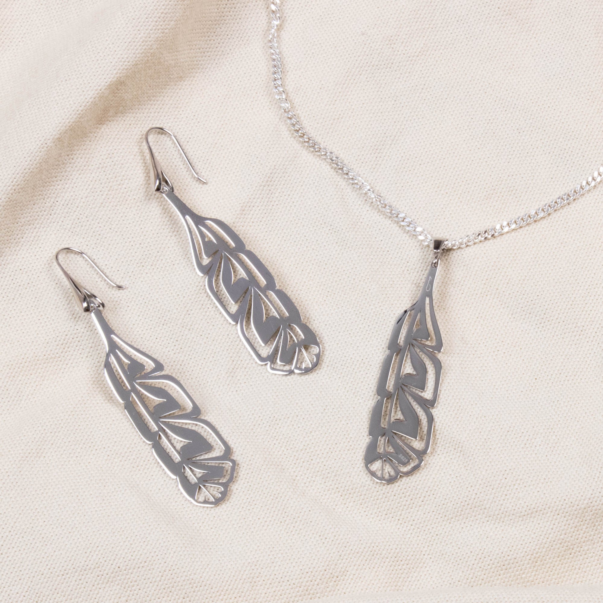 Sterling silver pendant and earring set on canvas background