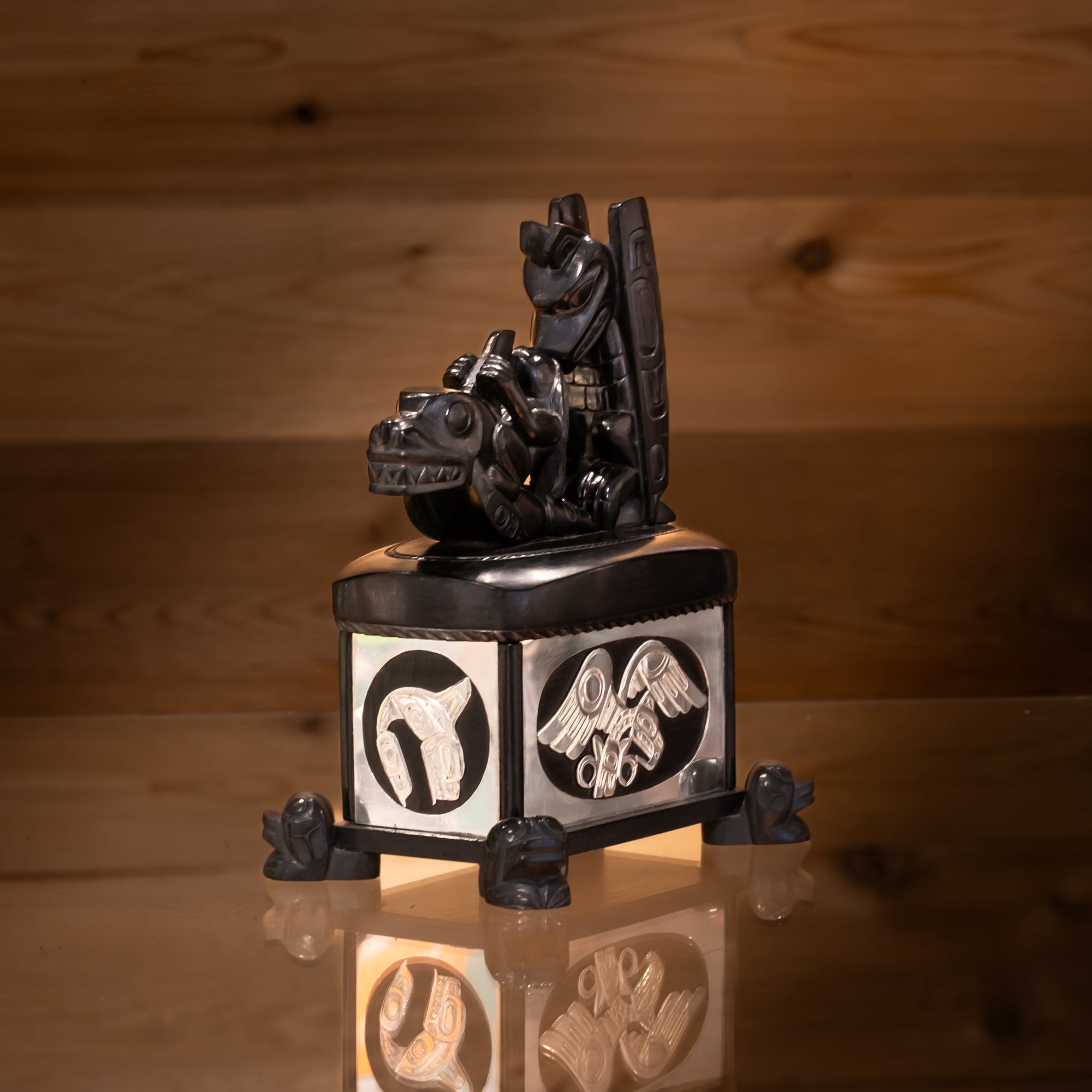 Front of Haida argillite killer whale and thunderbird argillite and sterling silver box done by Haida artist Ding Hutchingson on a dark wood background