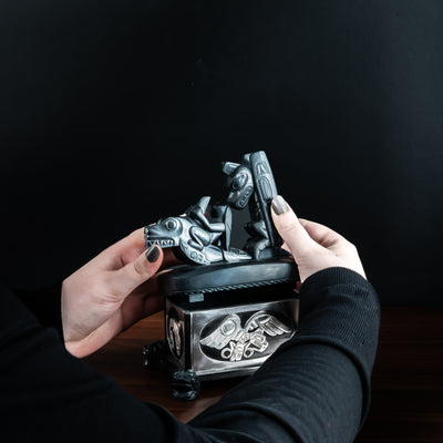 Person opening Haida argillite killer whale and thunderbird argillite and sterling silver box done by Haida artist Ding Hutchingson on a dark background