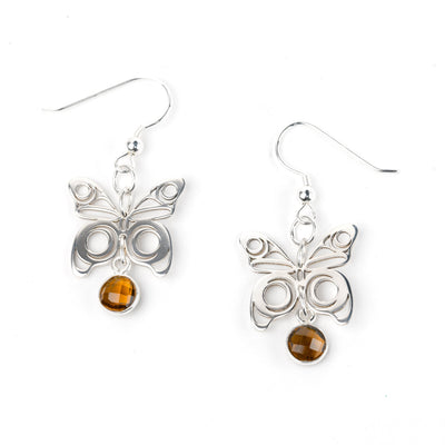 Butterfly-shaped earrings with amber stones on a white background