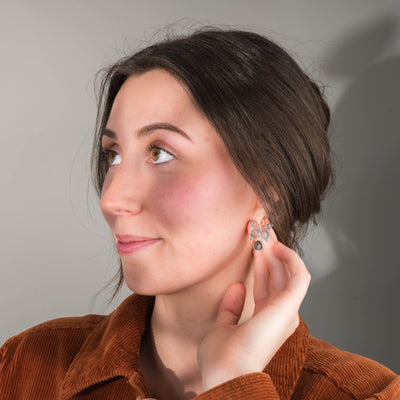 Woman wearing earrings, looking to the side against a neutral background