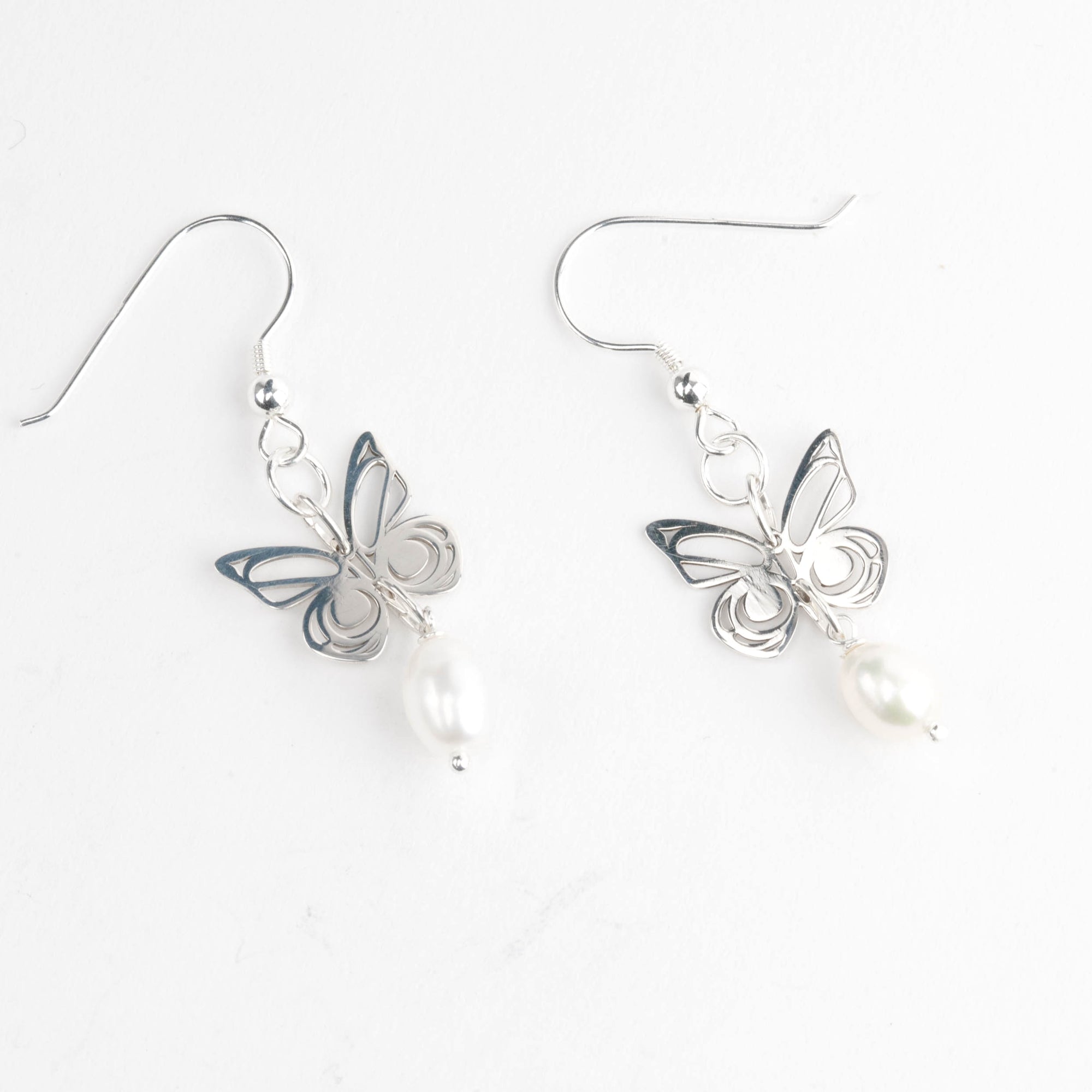 Butterfly-shaped earrings with pearl-like beads on a white background
