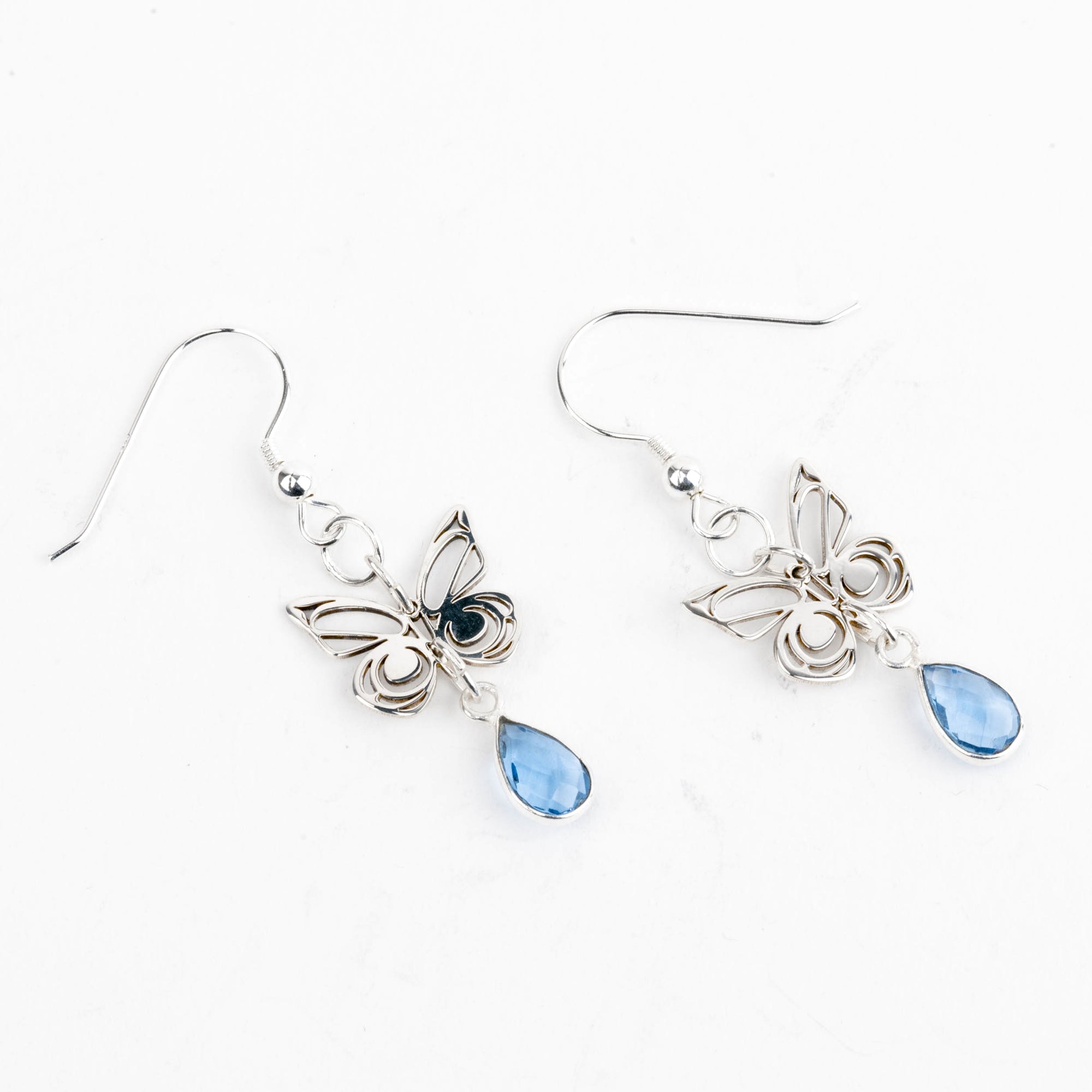 Butterfly-shaped earrings with blue teardrop charms on a white background