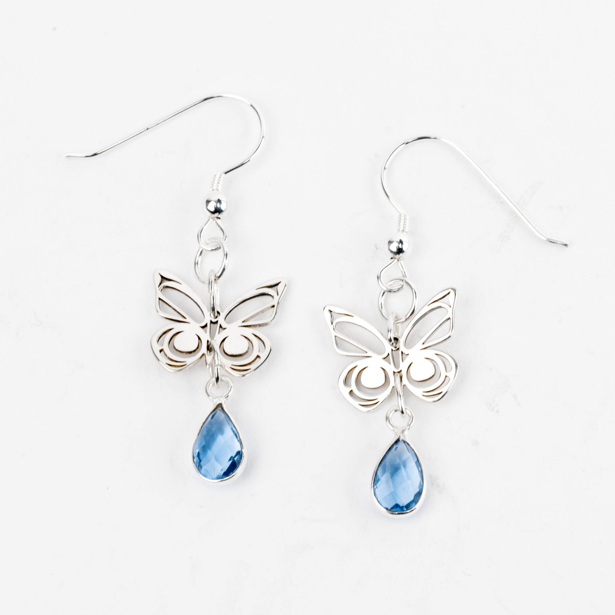 Butterfly earrings with blue teardrop-shaped stones on a white background