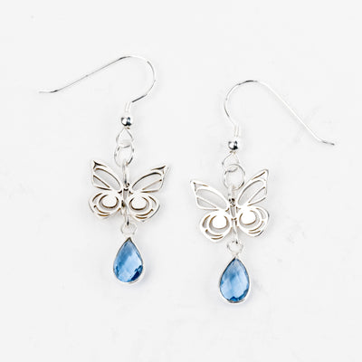 Butterfly earrings with blue teardrop-shaped stones on a white background