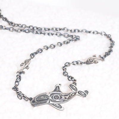 Silver necklace with a killer whale pendant  and salmon on a white background by Native Canadian artist morgan Asoyuf