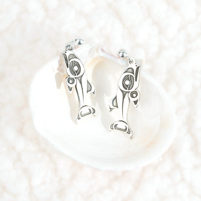 Sterling Silver Salmon earrings on a clam shell on a white cloud like background by Native artist Morgan Asoyuf
