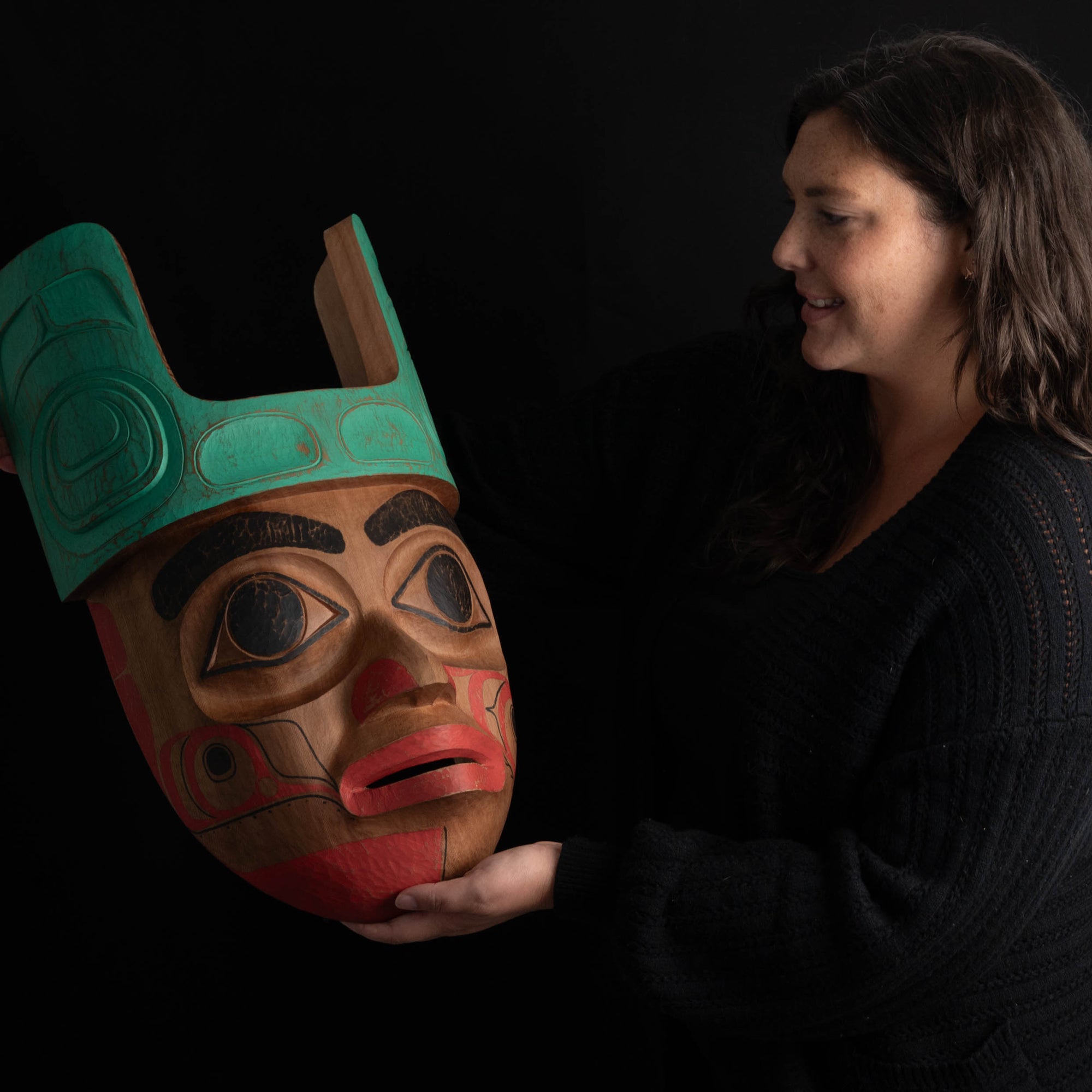 Ornate Cedar Mouse Woman mask with teal top and black and red face done by Haida artist Corey Bulpitt on a black background