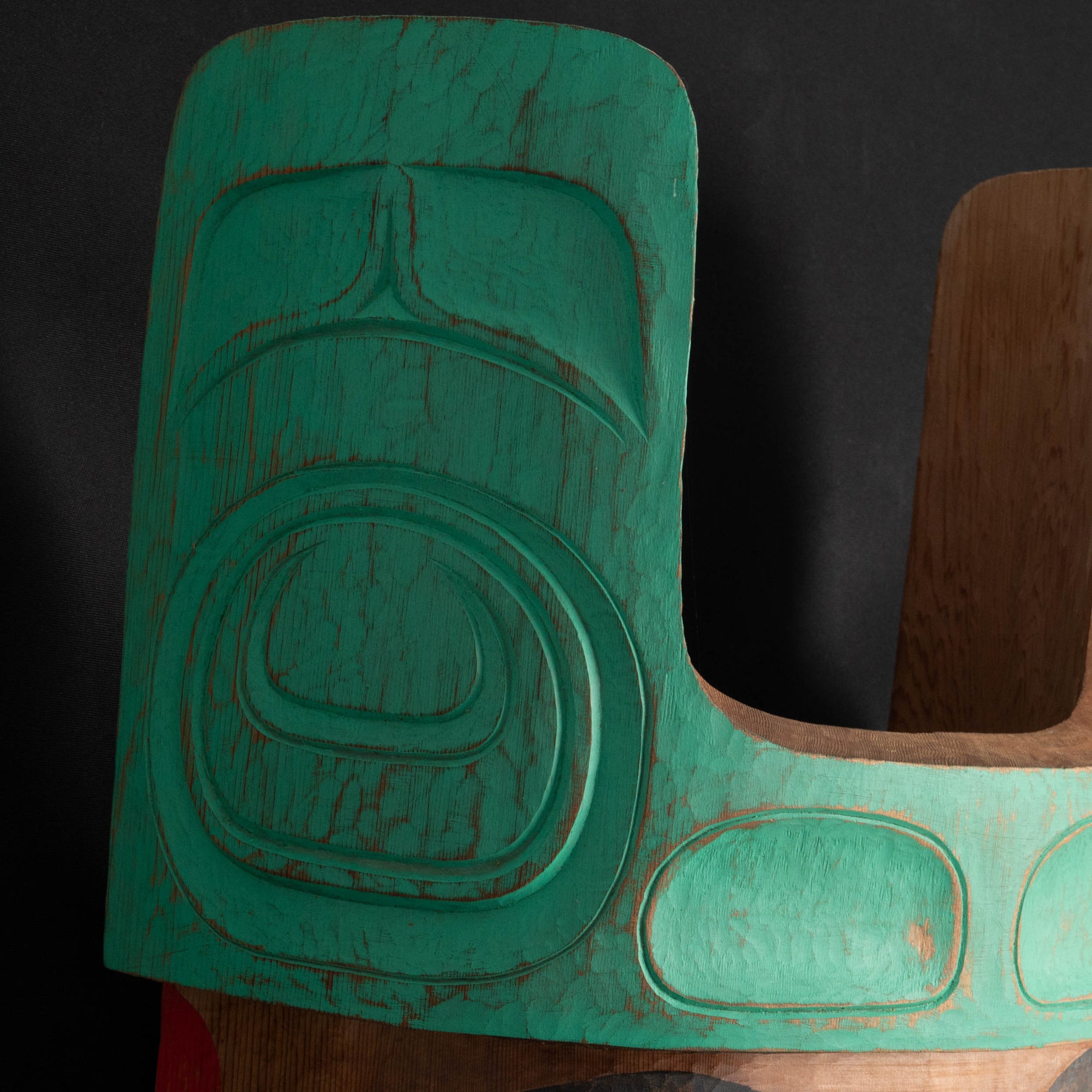Close-up of a teal and cedar Mouse Woman mask with teal top and black and red face done by Haida artist Corey Bulpitt on a black background