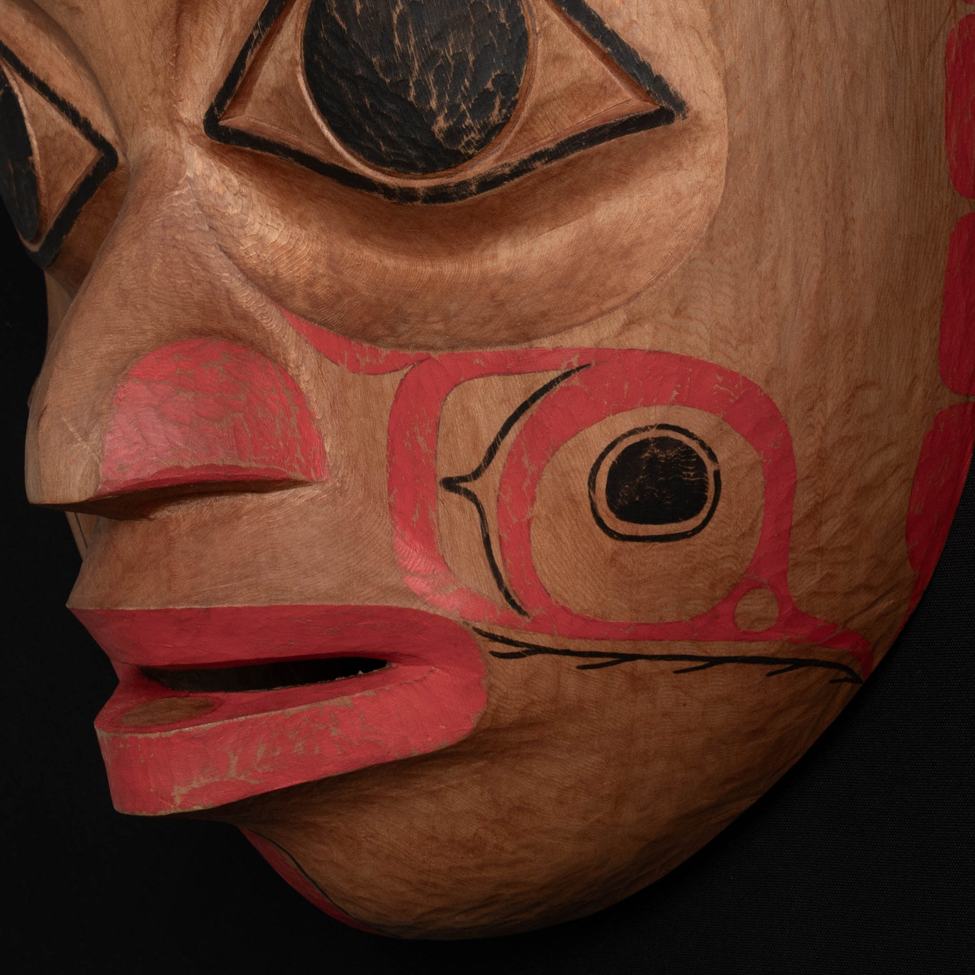 Right close up of Ornate Cedar Mouse Woman mask with teal top and black and red face done by Haida artist Corey Bulpitt on a black background