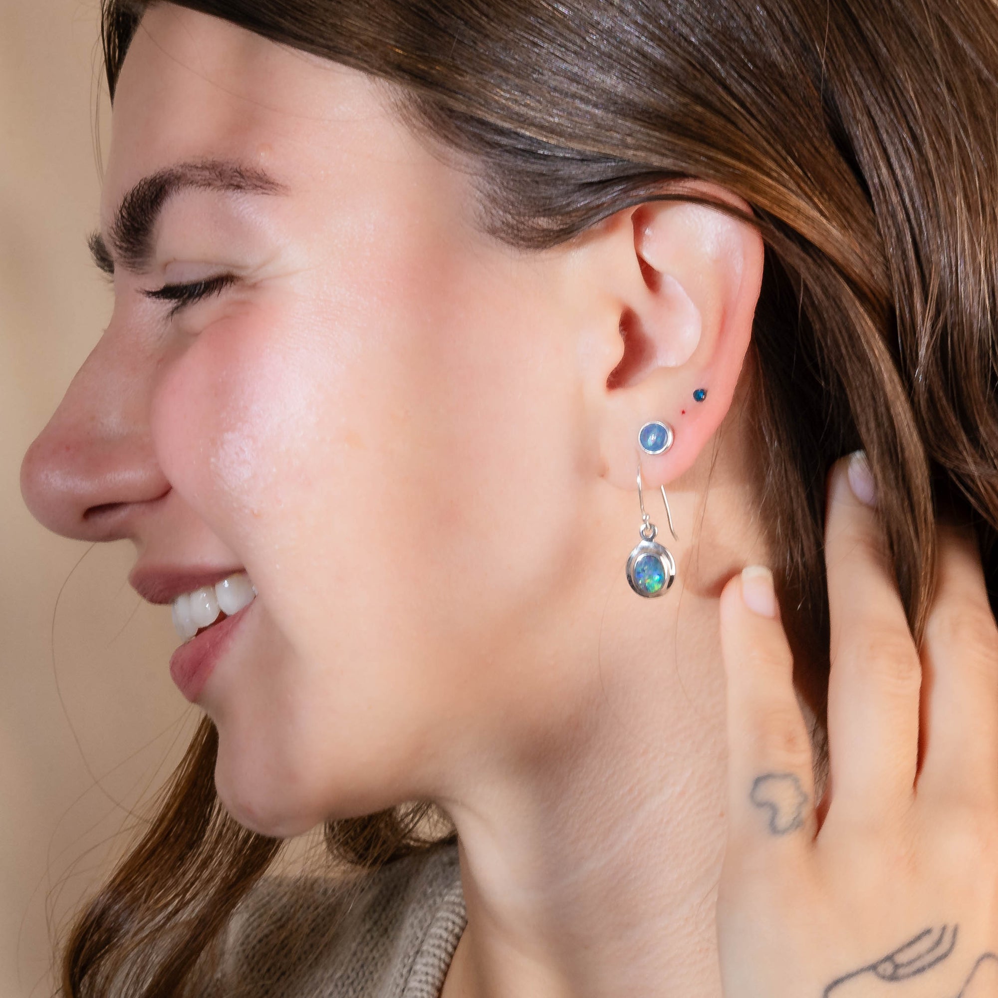 Close-up of a woman wearing a silver earring with colorful gemstones.
