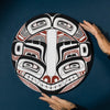 Hands that are holding a round northwest coast Haida style painting by Shoshannah Greene.