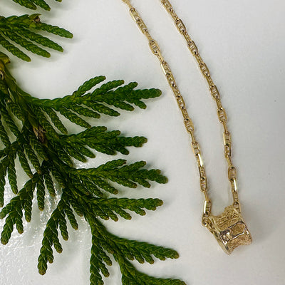 10k gold Salmon bone vertebrae on chain  shown on a white back ground with a cedar sprig
