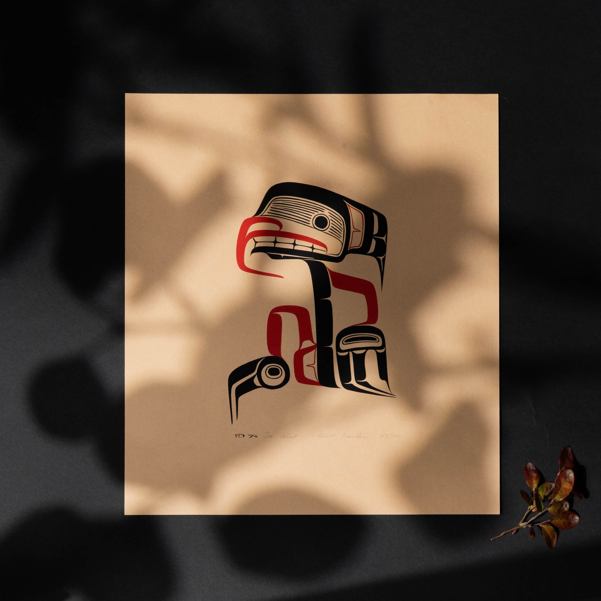 Artistic depiction of a stylized Haida Sea Ghost with red and black patterns on a beige background