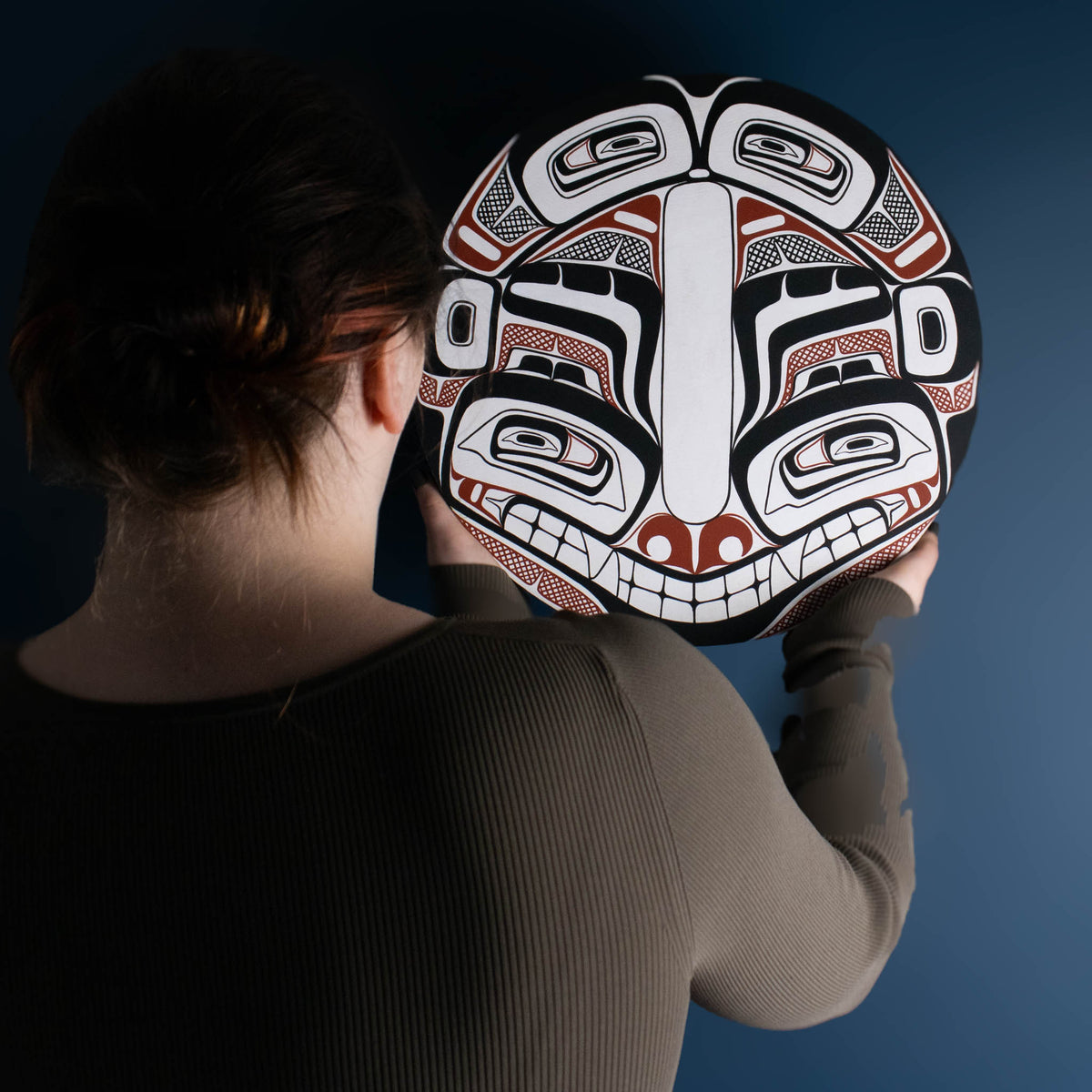 Sea Grizzly panel by Local Haida Gwaii artist Shoshannah Green hand painted on wood. In traditional black red and white. Held by model admiring it