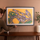 Person hanging a framed abstract artwork on a wall