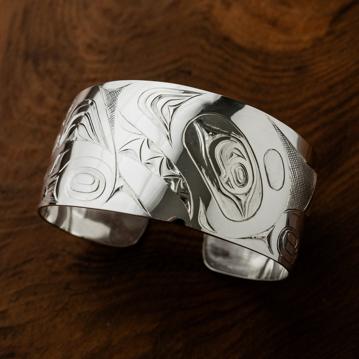 Men's 1.5 inch wide sterling silver orca killer whale bracelet by northwest coast Haida artist James Sawyer. Sold by Crystal Cabin Gallery on Haida Gwaii.