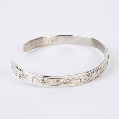 Side view of Sterling Silver Bracelet with flowers and a 14k gold hummingbird formline head made by first nations artist Agnes Seaweed Wisden