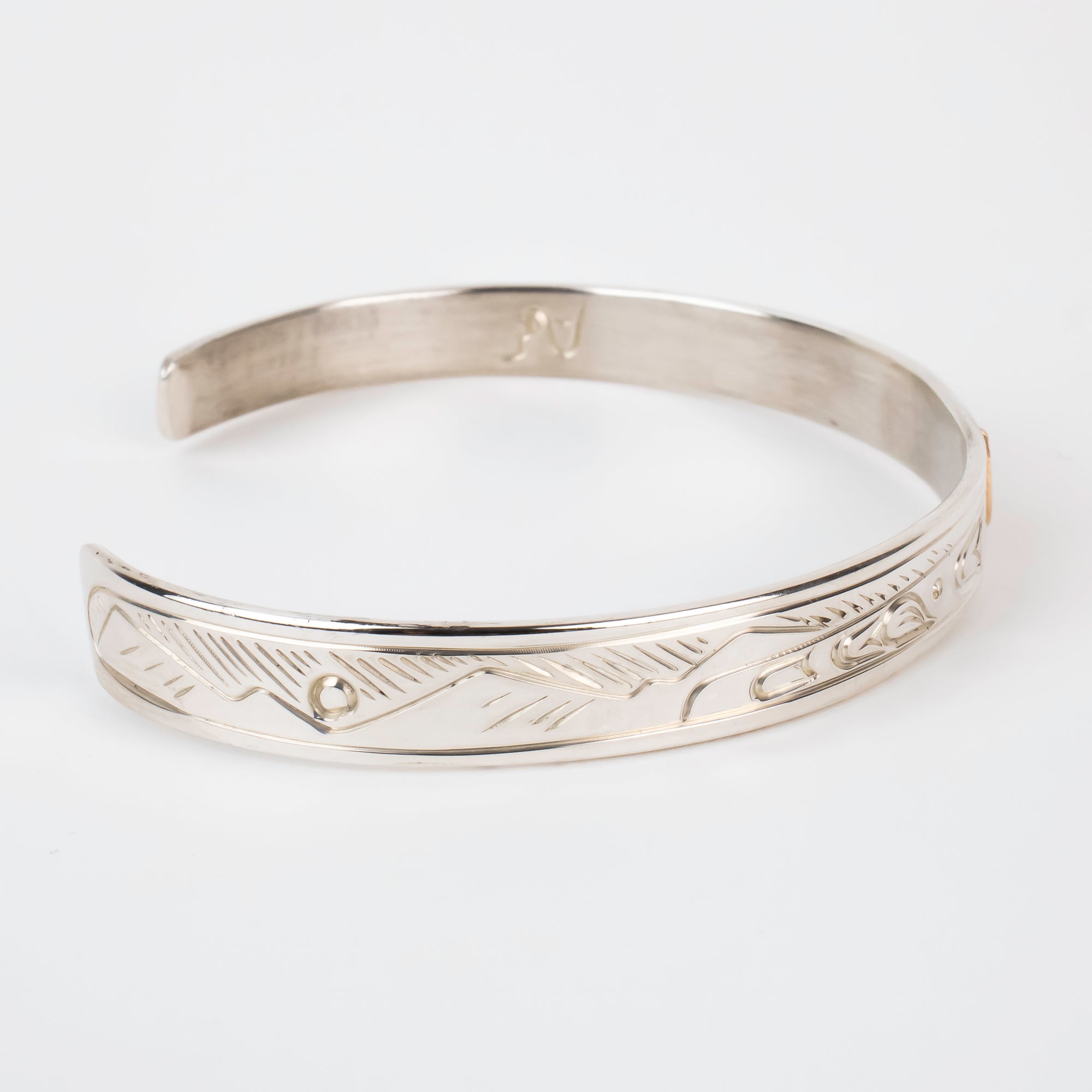 Side view of mountains on Sterling silver Bracelet featuring  14k gold formline wolf head, with mountains and trees hand carved around the bracelet