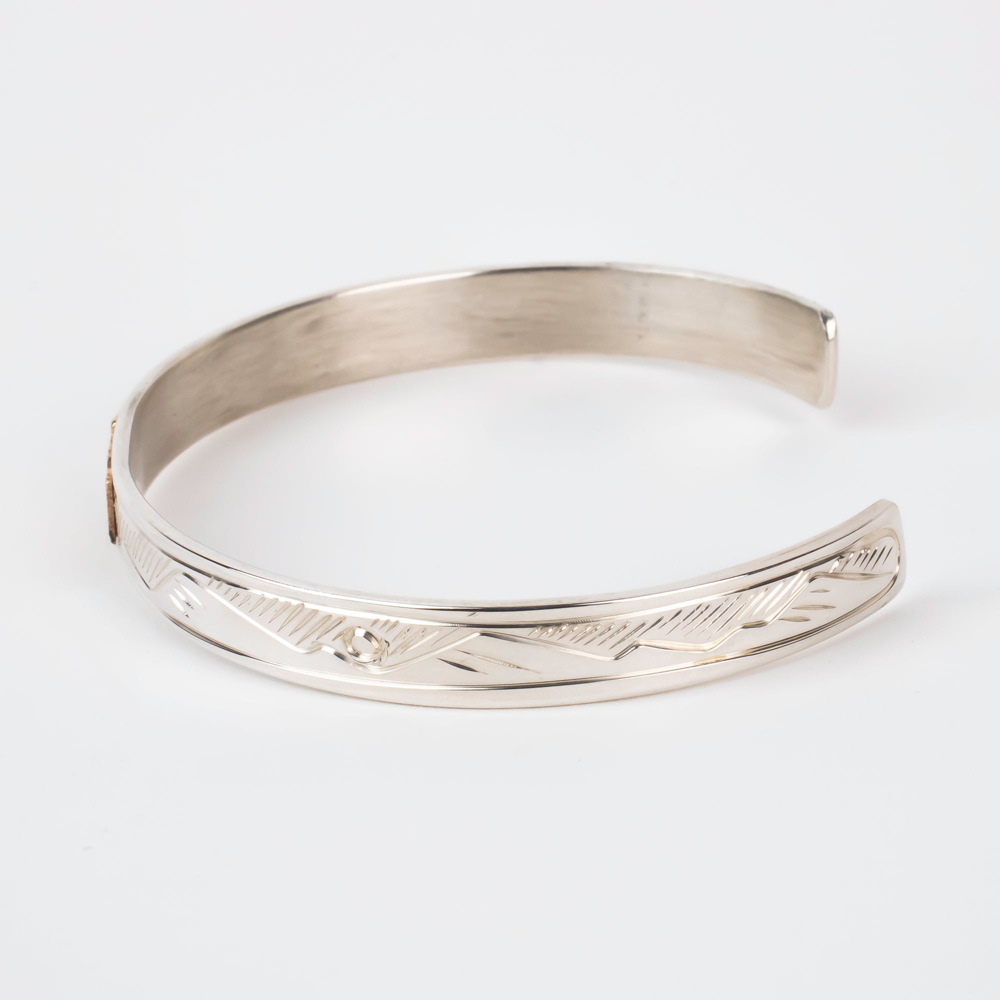 Side view of mountains on Sterling silver Bracelet featuring  14k gold formline wolf head, with mountains and trees hand carved around the bracelet