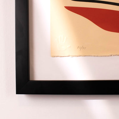 Framed fine artwork of a stylized bird with red, green, and black colors on a beige background by Haida Artist Robert Davidson showing the embossed hand print