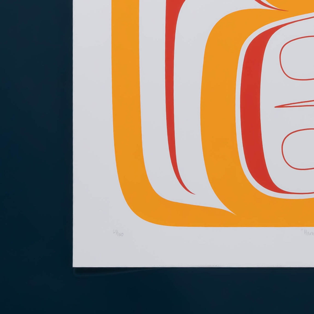 A close-up of a white art print featuring a bold orange design, a red and orange circular graphic element, and the edition number written in faint grey pencil.