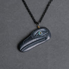 Carved black raven pendant with shimmering eye and black chain on a dark background facing to the right.