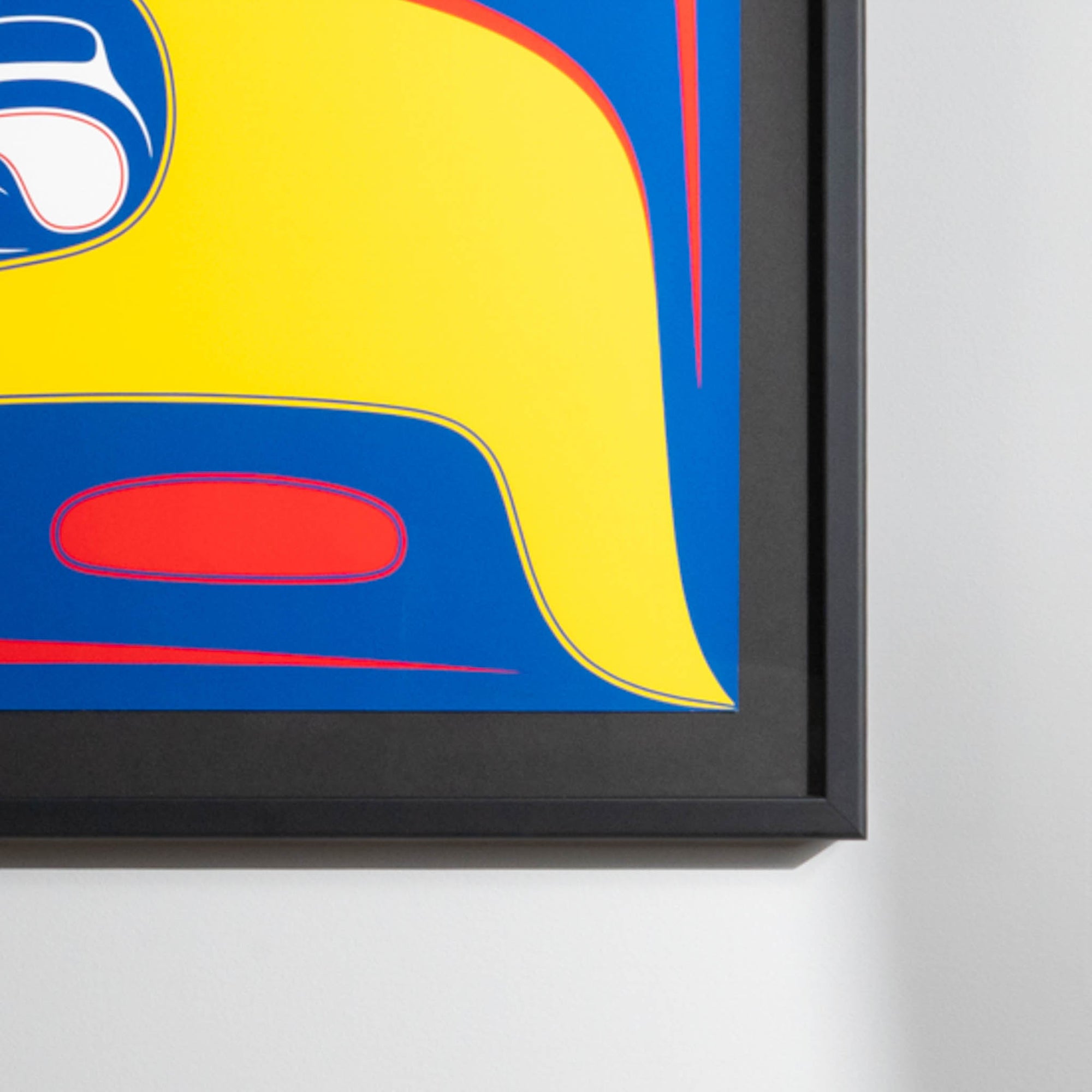 Close-up of bottom right framed yellow, blue and red art print.