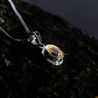 Close-up of a yellow citrine and sterling silver necklace on a dark brown and green background