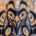 A close-up of a painted artwork featuring a stylized raven in dark navy blue and warm tan, surrounded by circular abstract patterns in tan, navy, white, and yellow.